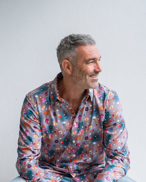 Man wearing a colourful patterned shirt against a plain background