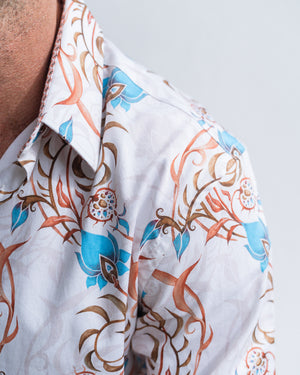Close-up of a person wearing a white shirt with blue and brown floral patterns on a light gray background