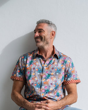 Man wearing a colourful patterned shirt against a plain background