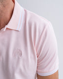 Close-up of a pink polo shirt with aJohn Lennon logo on a plain background