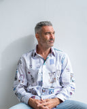 Man wearing a patterned shirt sitting against a plain background