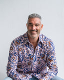 Man wearing a pink patterned shirt against a plain background