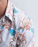 Close-up of a person wearing a white shirt with blue and brown floral patterns on a light gray background
