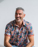 Man wearing a colourful patterned shirt against a plain background