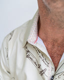 Close-up of a person wearing a light-colored shirt with text and graphics on the collar and chest.
