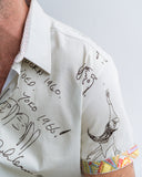 Close-up of a person wearing a white shirt with black text and drawings on a plain background