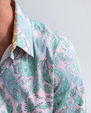 Close-up of a person wearing a pink shirt with green paisley pattern.