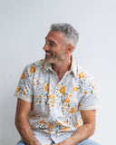 Man wearing a floral shirt sitting against a plain background