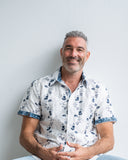 Man wearing a white floral shirt against a plain background