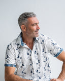 Man wearing a white floral shirt against a plain background