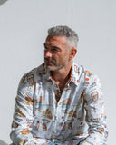 Man wearing a patterned John Lennon inspired shirt against a white background