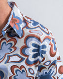 Close-up of a patterned shirt with blue, brown, and white design on a plain background